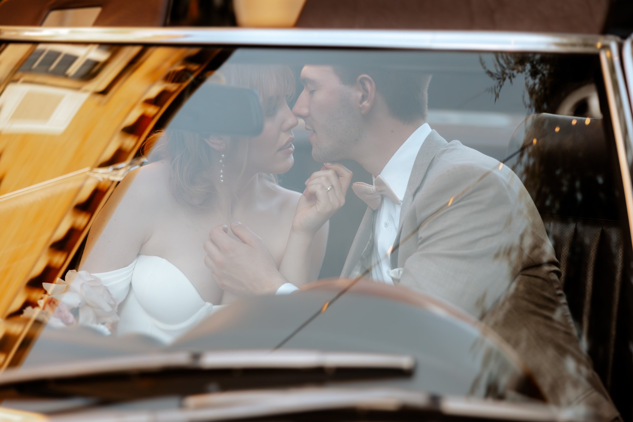 Hochzeitsbild von Hochzeitspaar im Hochzeitsauto. Schwandorf in der Oberpfalz. Bräutigam und Braut küssen sich im Auto an ihrer Hochzeit. Hochzeitsfotografin aus Schwandorf macht das Foto.